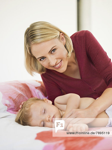 Woman near her baby sleeping on the bed