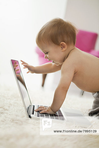 Baby Junge spielt mit einem Laptop