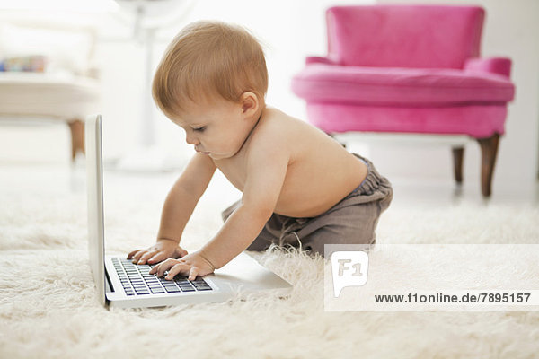 Baby Junge spielt mit einem Laptop