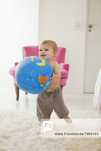Kleiner Junge spielt mit einem Globusball