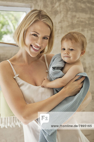 Lächelnde Frau hält ihr Baby im Handtuch