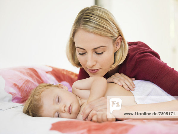 Woman looking at her baby sleeping on the bed