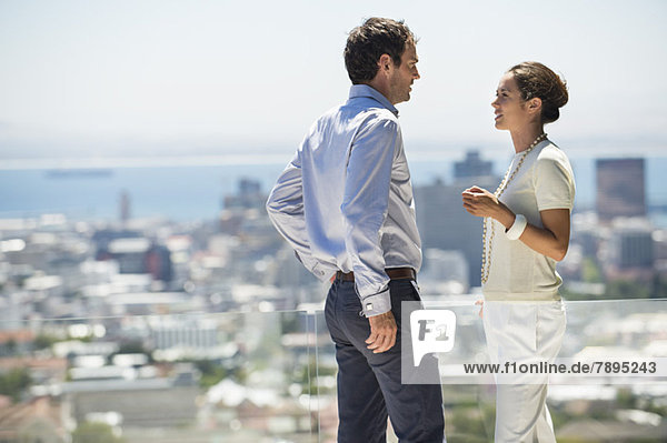 Couple discussing on a terrace with city in the background