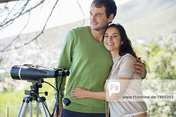 Couple smiling beside a binoculars on tripod