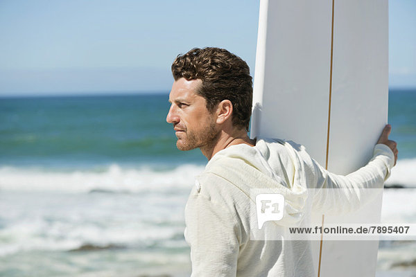 Man holding a surfboard on the beach