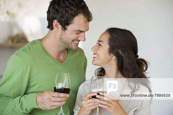 Paar hält Weingläser und lächelt