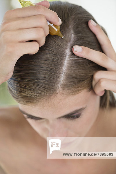 Woman applying oil into her hair