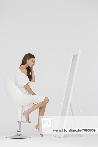 Woman sitting on a chair and looking at mirror