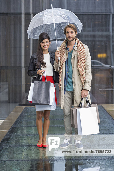 Paar stehend mit Einkaufstaschen bei Regen