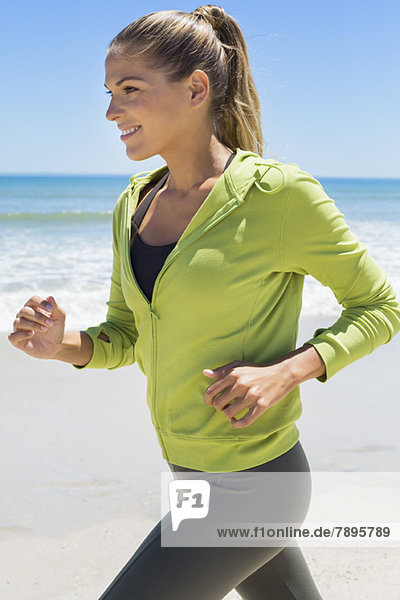 Smiling woman running on the beach