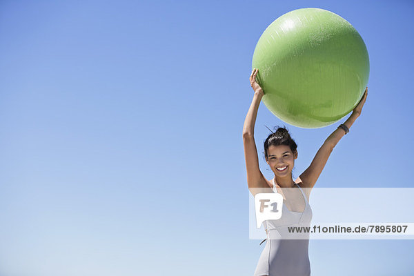 Schöne Frau mit einem Fitnessball am Strand