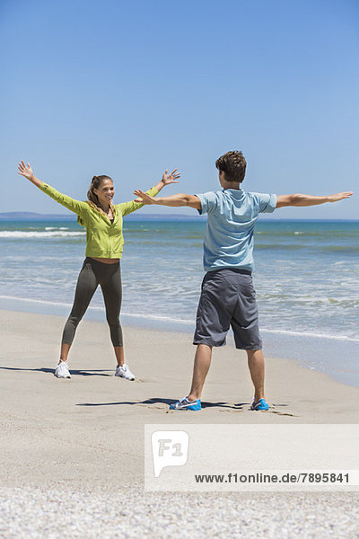 Woman and her coach exercising on the beach