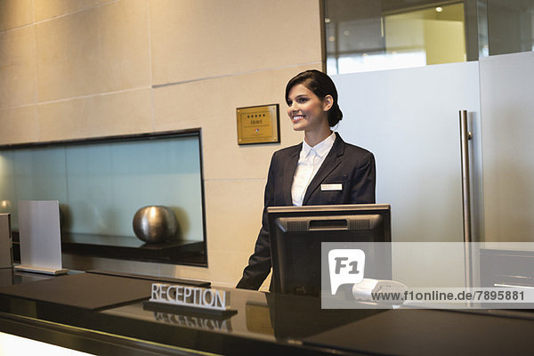 Receptionist standing at the hotel reception counter and smiling