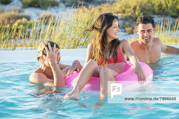 Drei Freunde genießen in einem Swimmingpool am Strand