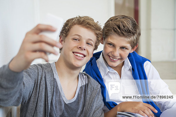 Two teenage boys taking a picture of themselves with a mobile phone
