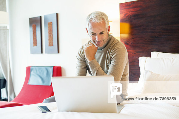 Man using a laptop in a hotel room