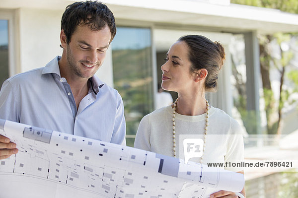 Couple holding a blueprint and smiling