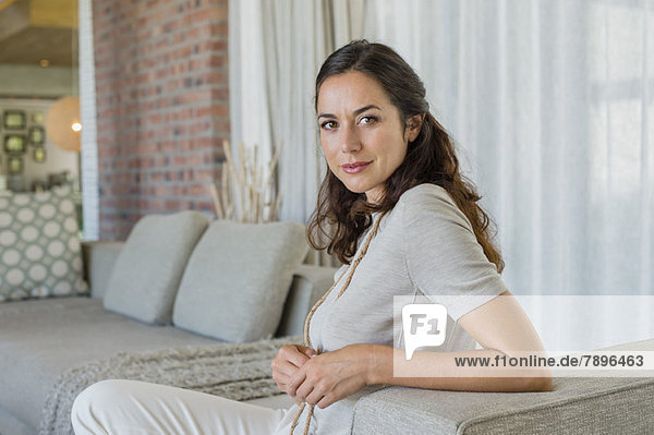 Porträt einer schönen Frau auf einer Couch sitzend