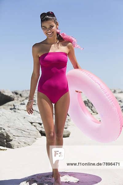 Beautiful woman holding an inflatable ring on the beach
