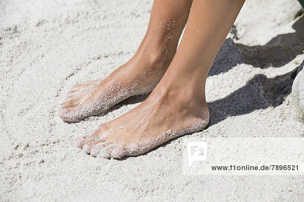 Frauenfüße im Sand am Strand