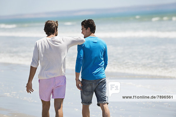 Zwei Männer  die am Strand spazieren gehen.