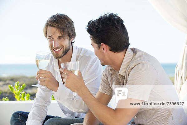 Zwei männliche Freunde genießen Weißwein im Freien