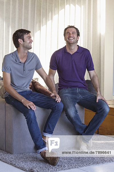 Two male friends smiling at home