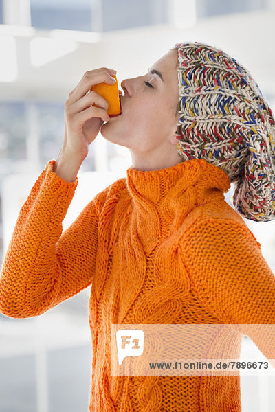 Frau drückt Saft aus einer Orange in den Mund