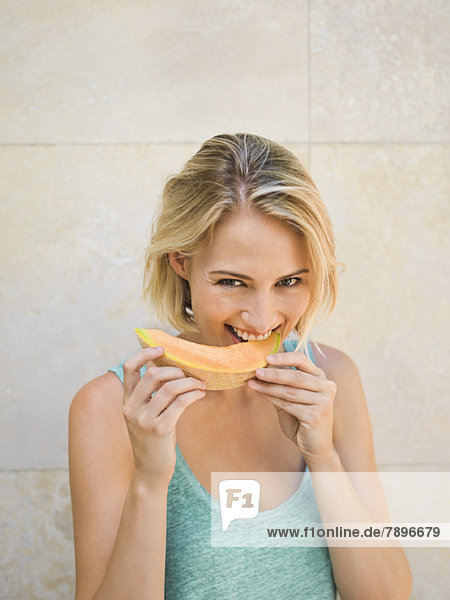 Smiling woman eating melon