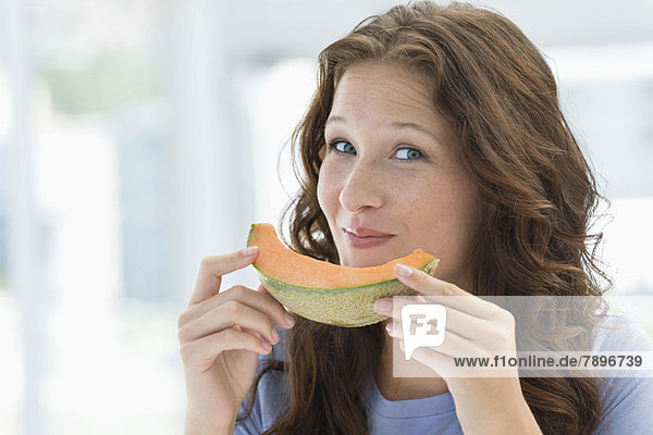 Porträt einer lächelnden Frau beim Melonenessen