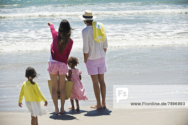 Kinder mit ihren Eltern beim Blick aufs Meer am Strand