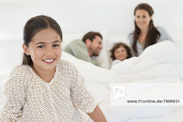 Porträt eines Mädchens  das mit seiner Familie im Hintergrund lächelt.