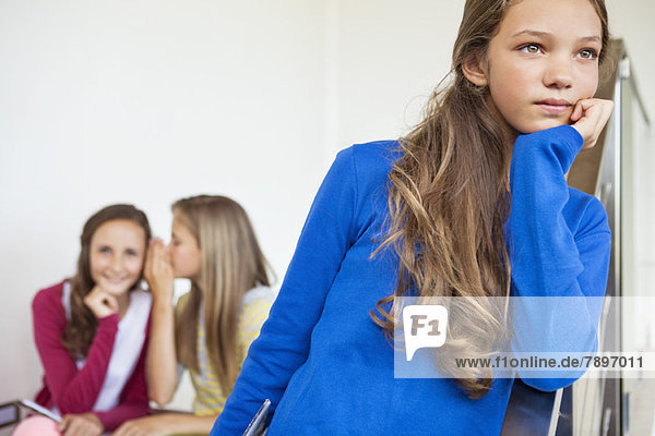 Close-up of a girl thinking with her friends whispering in the background