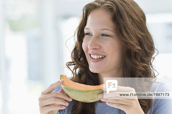 Nahaufnahme einer lächelnden Frau beim Melonenessen