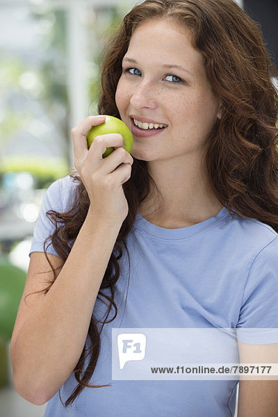 Woman eating a green apple and smiling