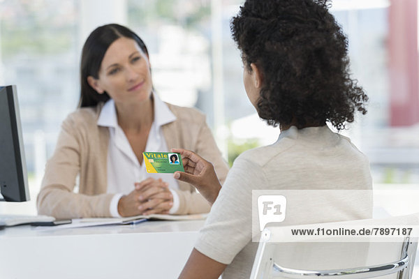 Female patient looking at a health insurance card