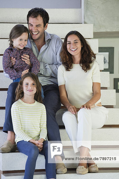 Familie sitzt auf der Treppe und lächelt