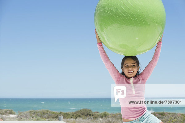 Mädchen mit Fitnessball am Strand