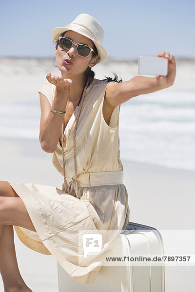 Beautiful woman taking a picture of herself with a cell phone on the beach