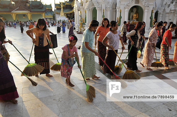 Frauen kehren als rituelle Handlung den Boden  Shwedagon-Pagode