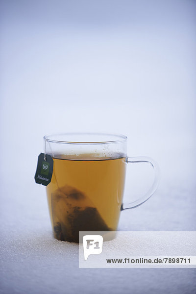 Teetasse mit Kräutertee steht im Schnee