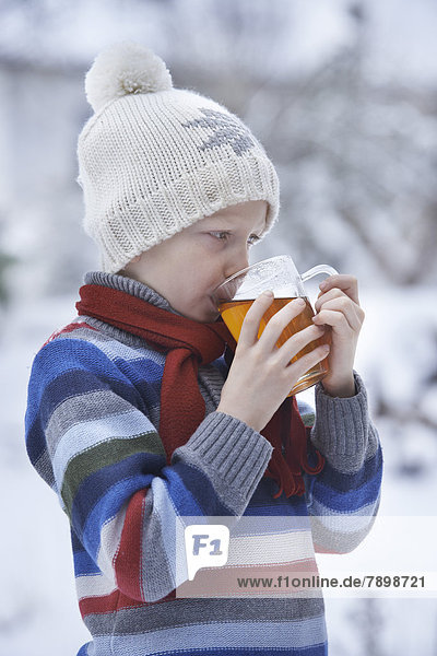 Junge in Winterkleidung trinkt Tee
