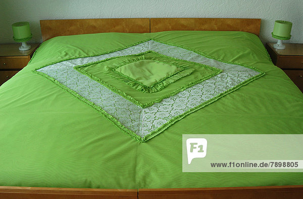 Doppelbett mit grüner Tagesdecke