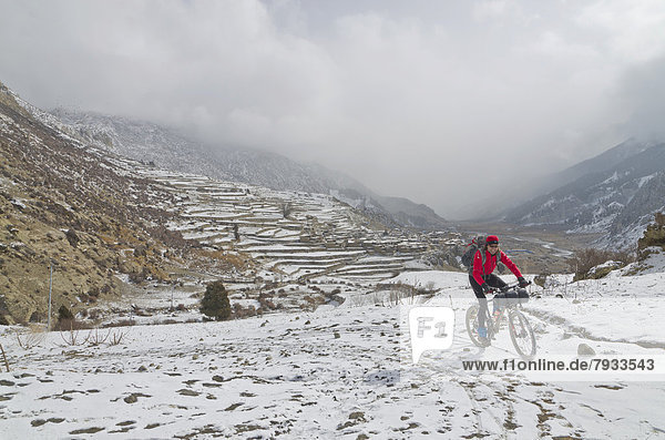 Radfahrer mit seinem Fahrrad im Schnee auf dem Weg zum Thorong La Pass 5416 m