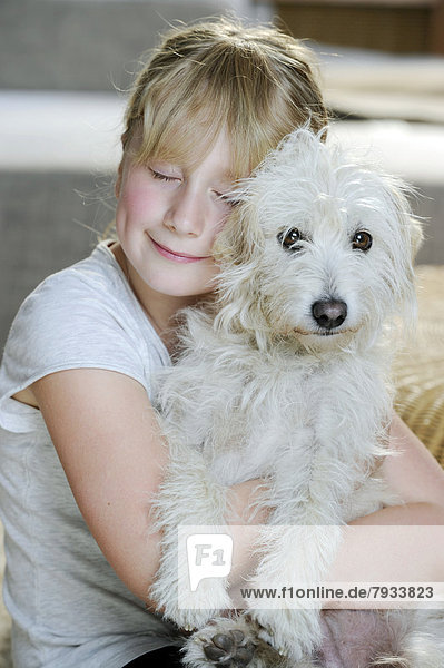 Girl  9  cuddling with a young mixed-breed dog