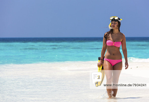 Junge Frau  etwa 20 Jahre  geht auf einer Sandbank  mit Schnorchelausrüstung