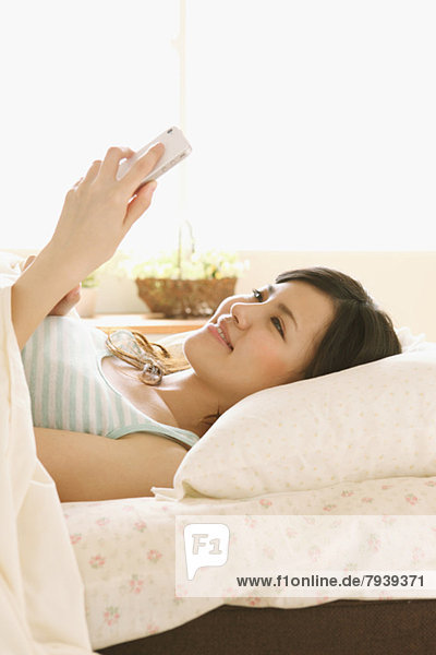 junge Frau junge Frauen Bett Smartphone