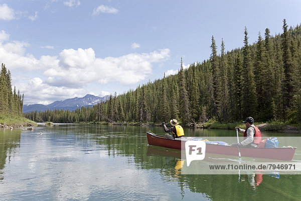 couple  man and woman paddling a canoe  canoing  upper Liard River  Yukon Territory