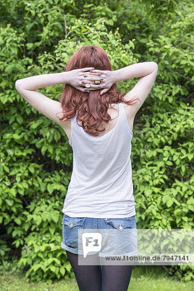 Back view of young woman crossing her hands behind her head