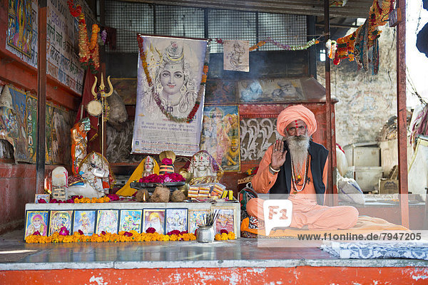 Ein Sadhu  heiliger Mann oder Wanderasket hockt im Lotussitz auf einer Matte in einem hinduistischen Gebetsschrein